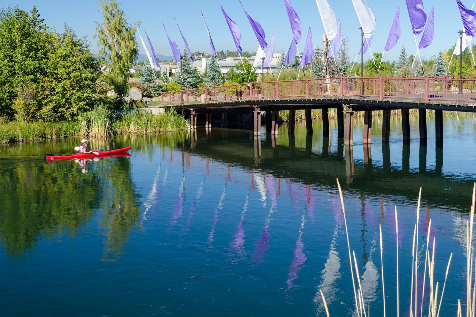 Kayakers paddling the Deschutes River by the footbridge in the Old Mill District