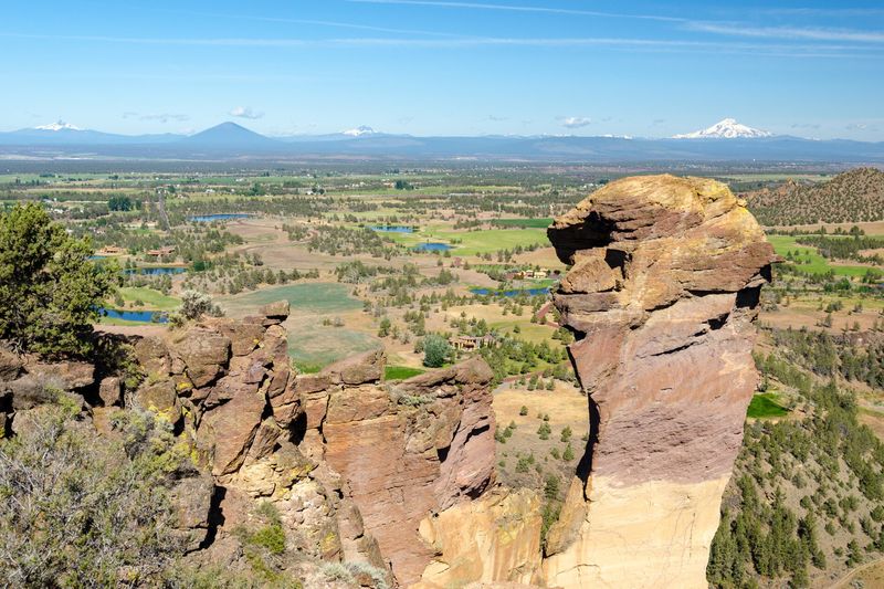 Monkey Face spire at Smith Rock with farmland and Cascade peaks beyond