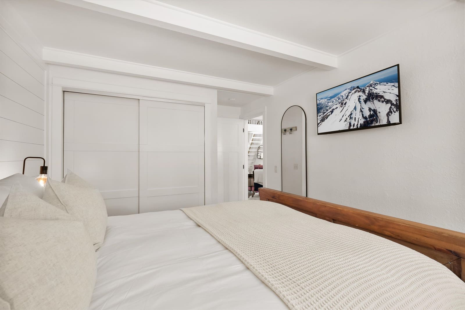 Bedroom one from the foot of the bed, with closet storage and a wall-mounted smart TV