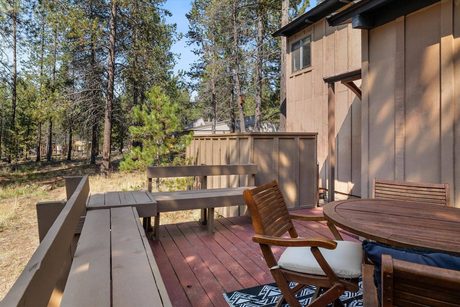 Back deck with a wood table and chairs looking out over the trees