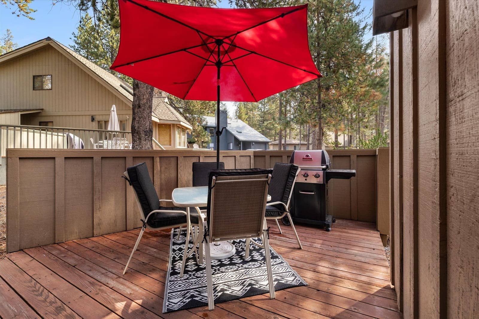 Deck with a red umbrella, patio dining set, and gas barbecue grill