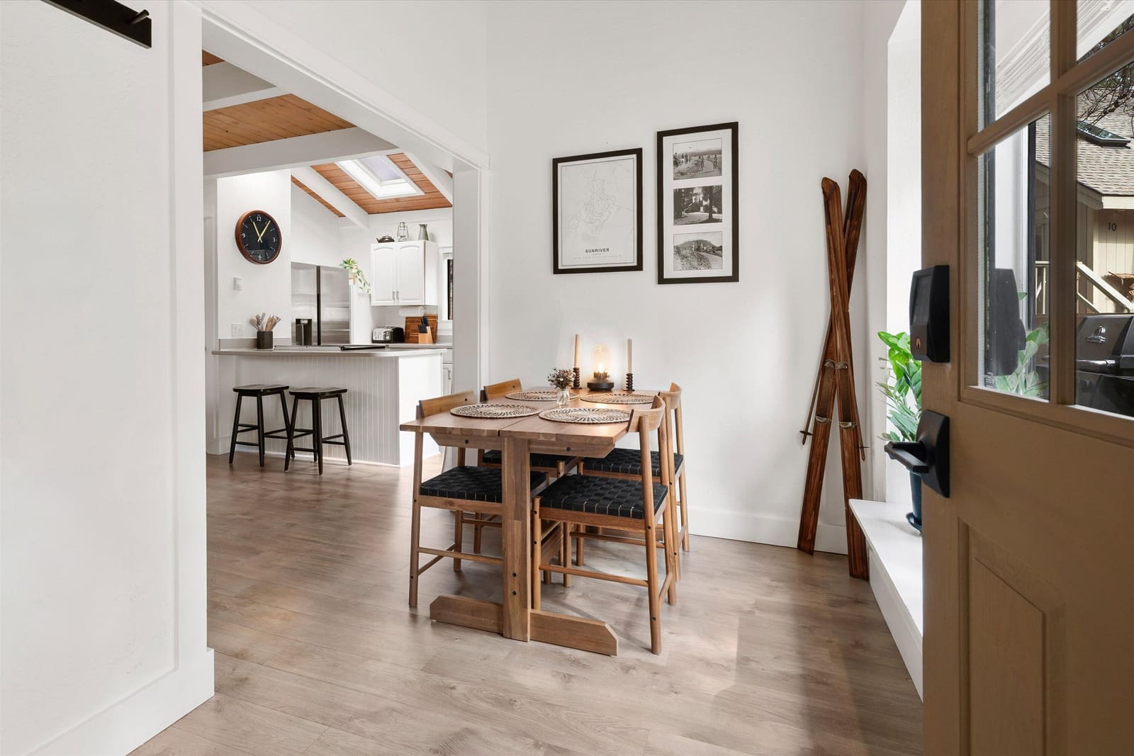 Dining table for four with vintage skis on the wall and the kitchen bar beyond