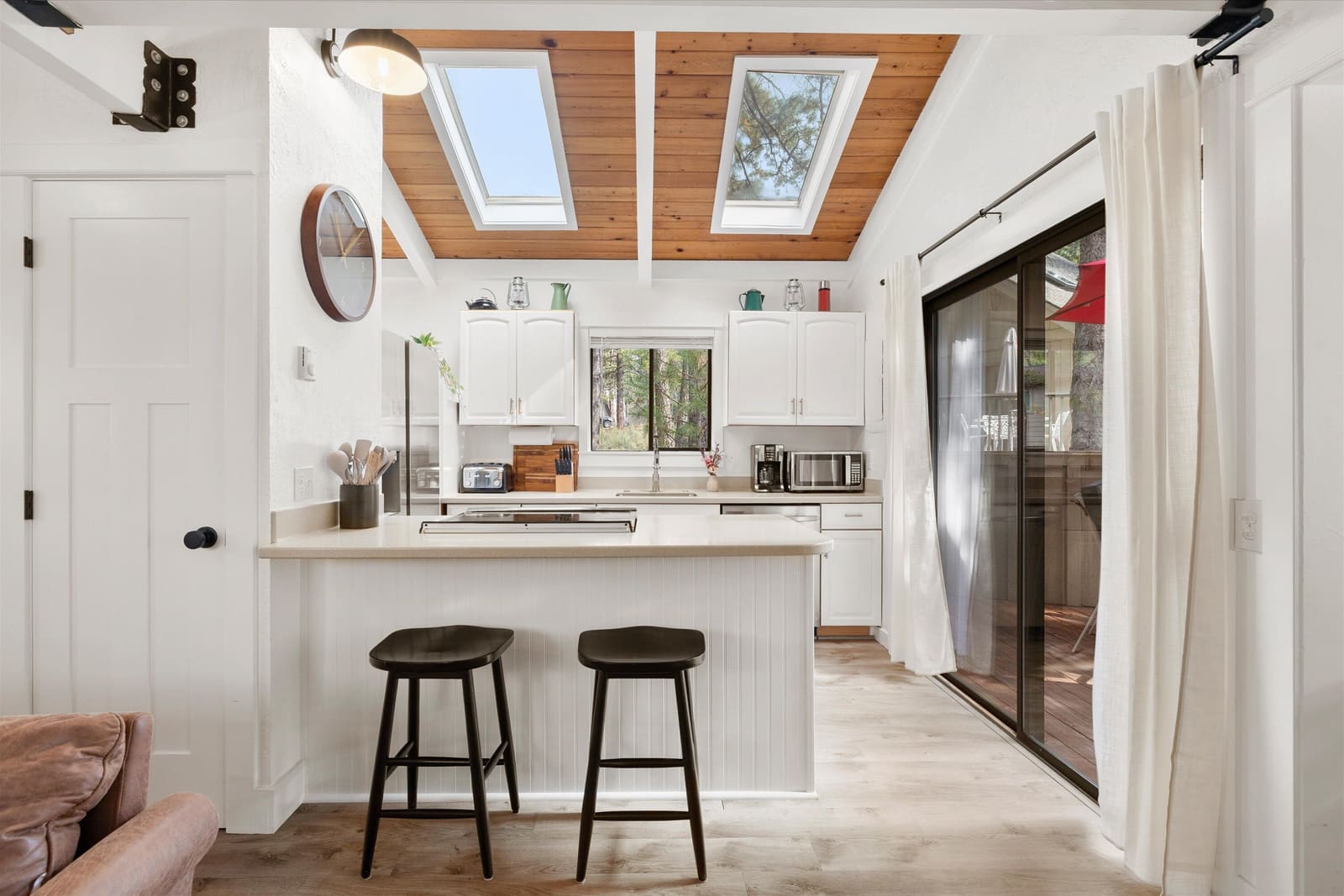 Kitchen breakfast bar with two stools under skylights, next to the sliding door to the deck