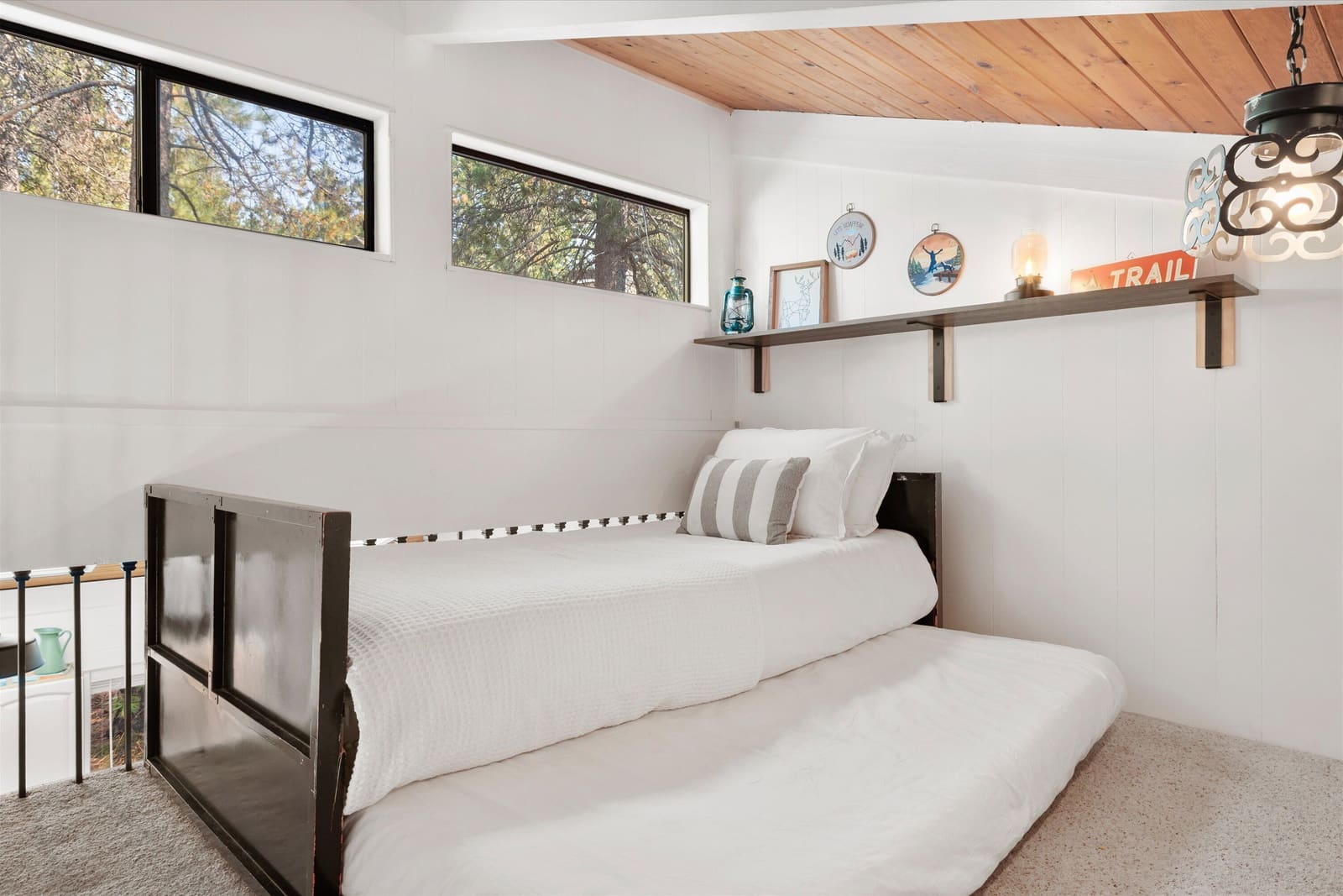 The loft with its two twin beds behind a safety railing, under a shelf of Cascade trail decor